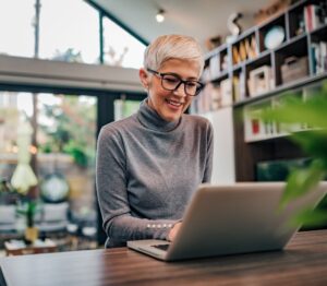 Portrait of a cheerful mature businesswoman working on laptop at home office.